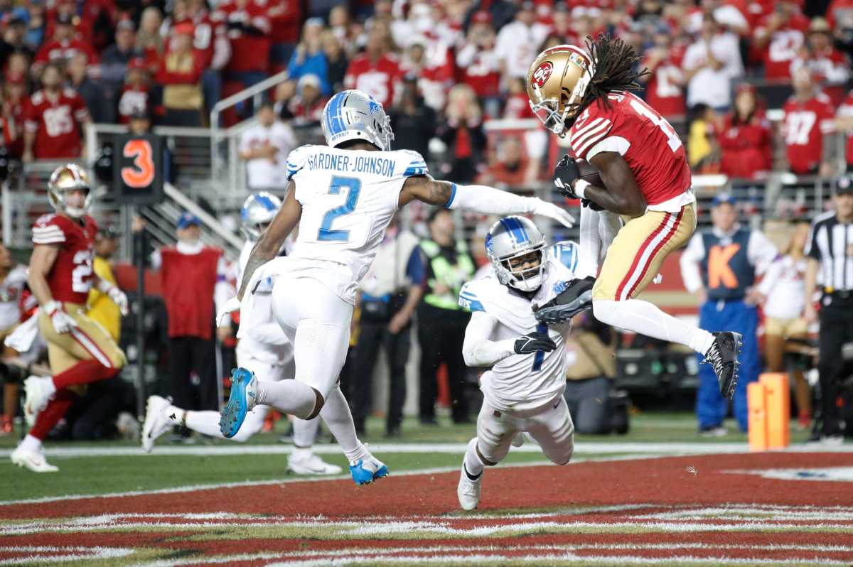 Brandon Aiyuk jumps to catch the ball in the end zone as two Lions players reach to tackle him